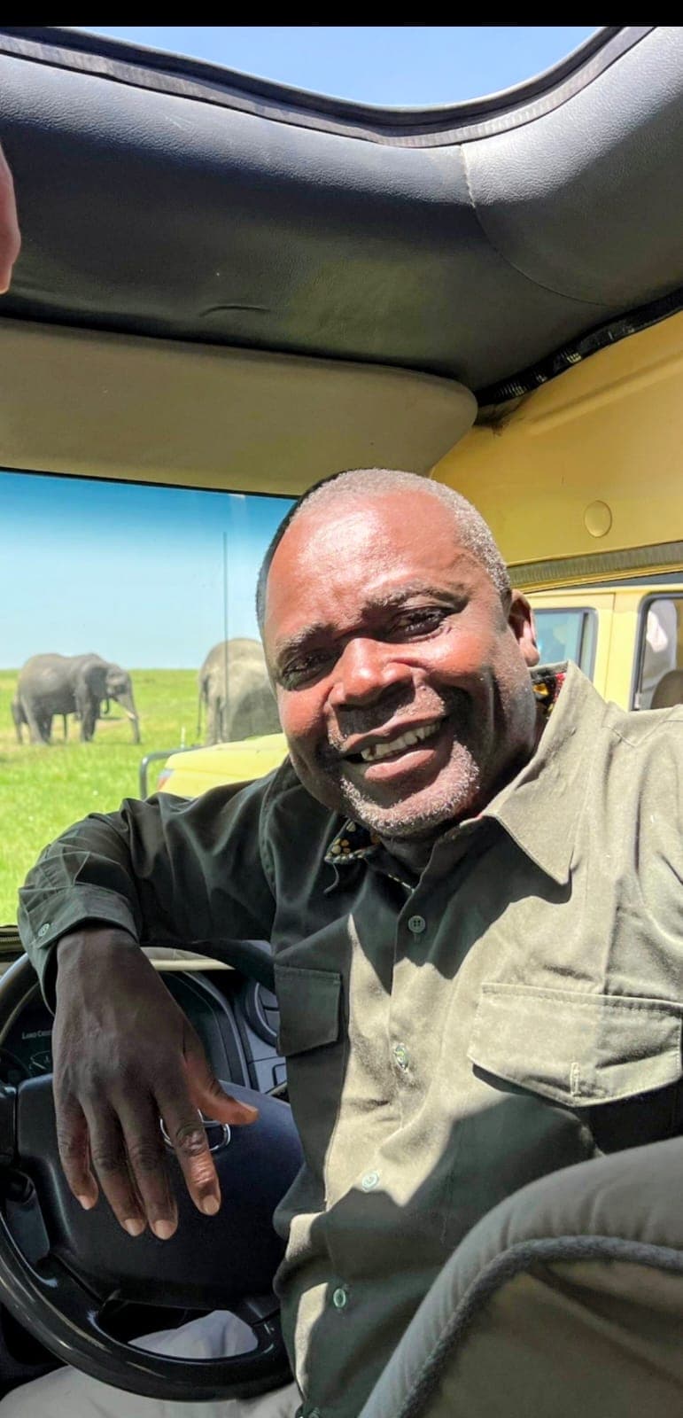 Jacob J. Unda in the field, Amboseli — elephants behind him